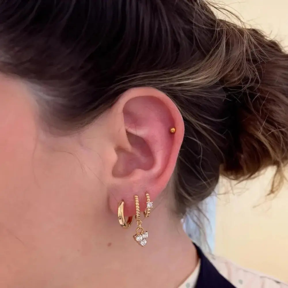 Close-up of an ear wearing gold hoop earrings with a blurred background