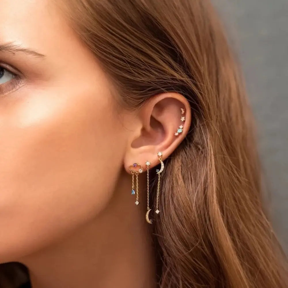 Close-up of a woman's ear with multiple earrings against a neutral background