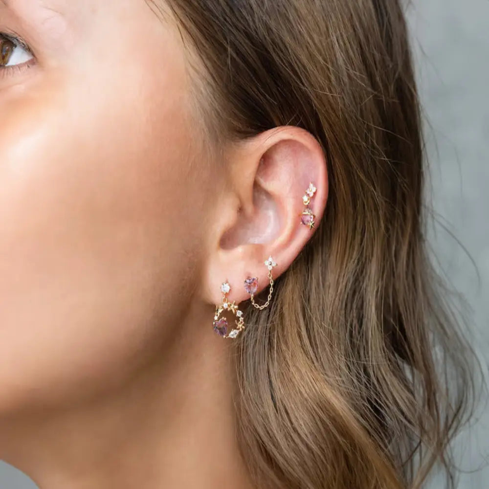 Close-up of a person wearing multiple earrings with a neutral background